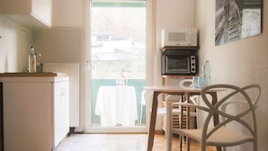 Een kleine keuken met een koelkast, magnetron en een eethoek met een tafel en stoelen.