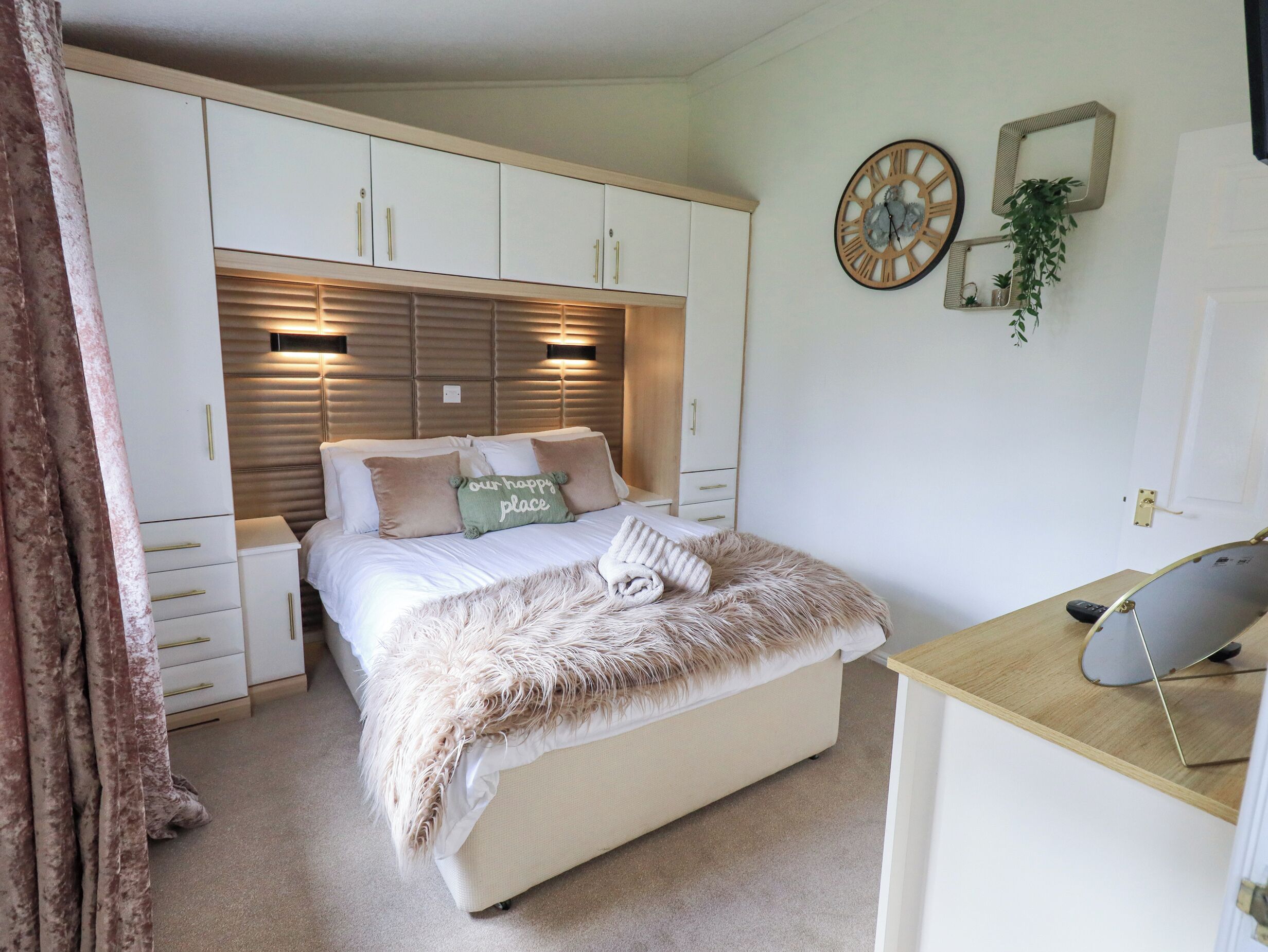 A bedroom with a bed, bedside table, and a desk.