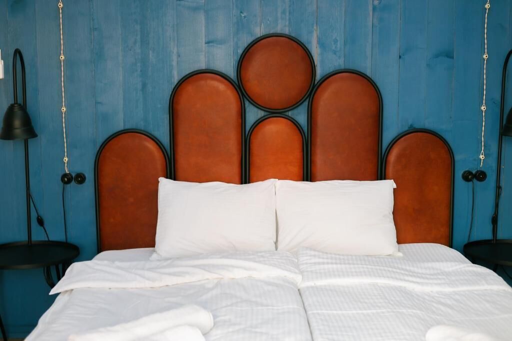A bed with a brown headboard and white bedding in a room with blue walls.