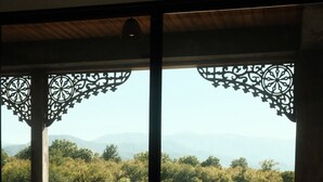 A balcony with a table, chair, and lamp, overlooking a mountainous landscape. - Chateau Vartsikhe  (Baghdati)