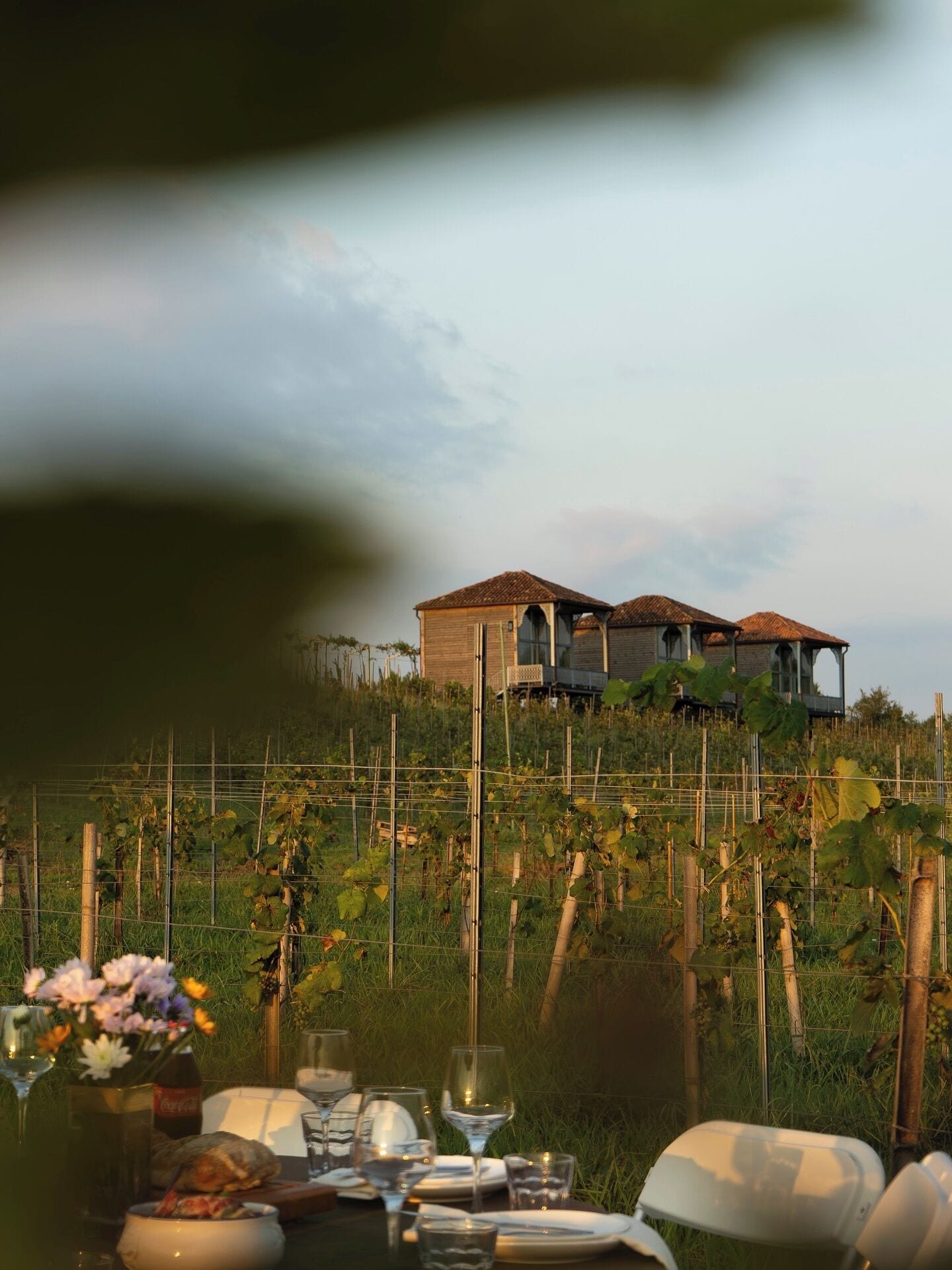 A table set for dining with a view of two wooden houses on a hillside.