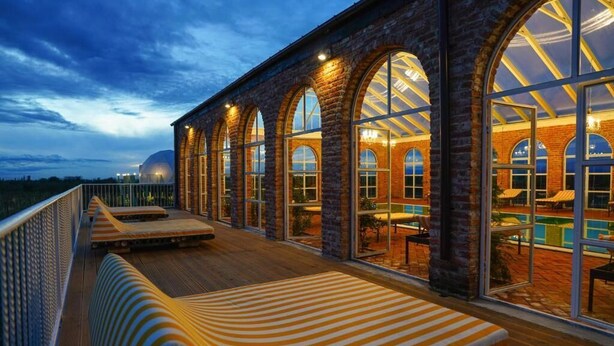 A hotel with a long, covered outdoor seating area with a pool and lounge chairs. - Chateau Vartsikhe  (Baghdati)