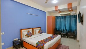 A hotel room with a bed, a desk, a chair, and an air conditioning unit. - Hotel Earthview II  (Noida)