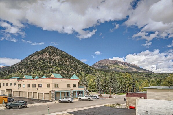 A building with a parking lot, a mountain in the background, and a clear sky.