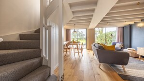 Amplia sala de estar con escaleras, piso de madera y un sofá moderno con cojines.