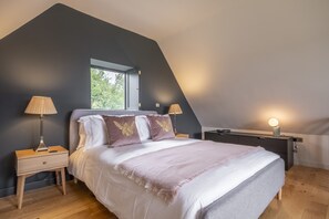 Een slaapkamer met een bed, twee nachtkastjes, een raam en een lamp.