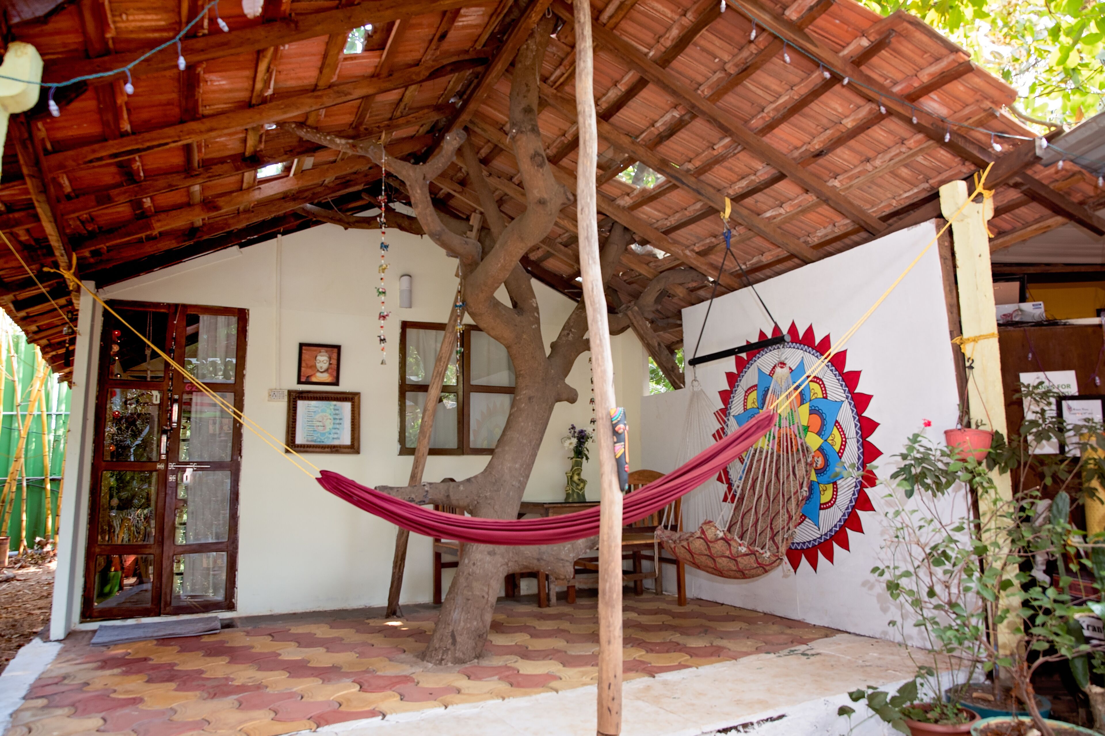 A covered outdoor area with a hammock, a tree, and a wall with a colorful mural.