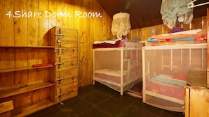 A 4-share dorm room with wooden walls, a wardrobe, and bunk beds. - Kranti Yoga Tradition (Canacona)