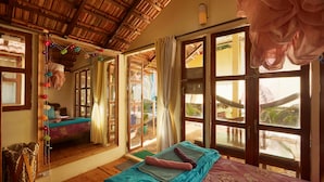 A room with a bed, a large mirror, and a view of the outside. - Kranti Yoga Tradition (Canacona)