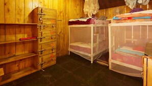 Dormitorio tipo albergue con capacidad para cuatro personas, paredes de madera, armario y camas literas.