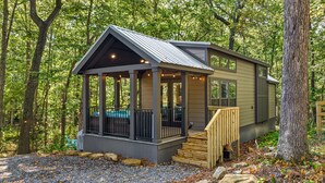 A cabin with a covered porch, a staircase, and a view of the surrounding forest.