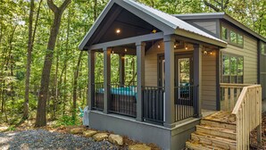 A small cabin with a porch, surrounded by trees.