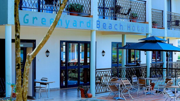 Un hôtel doté d’une terrasse et d’une enseigne indiquant « Greenyard Beach Hotel ».