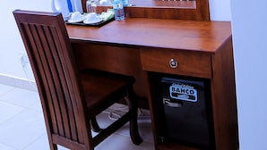Un bureau en bois avec une chaise, un petit coffre-fort étiqueté « BAHCO » et une bouteille d’eau posée sur le bureau.