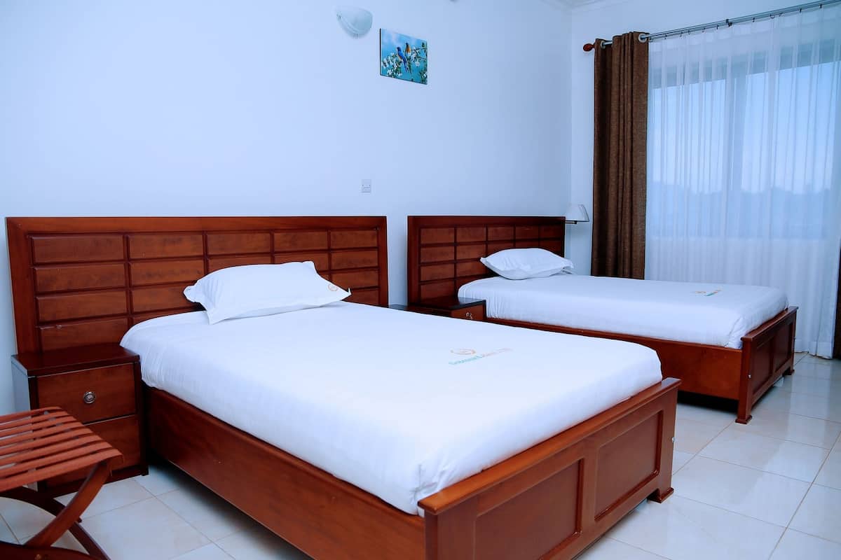 A hotel room with two wooden beds, white bedding, a small wooden table, and a nightstand.