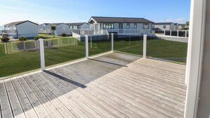Une terrasse en bois offrant une vue sur un quartier résidentiel, avec des maisons et une pelouse verdoyante.