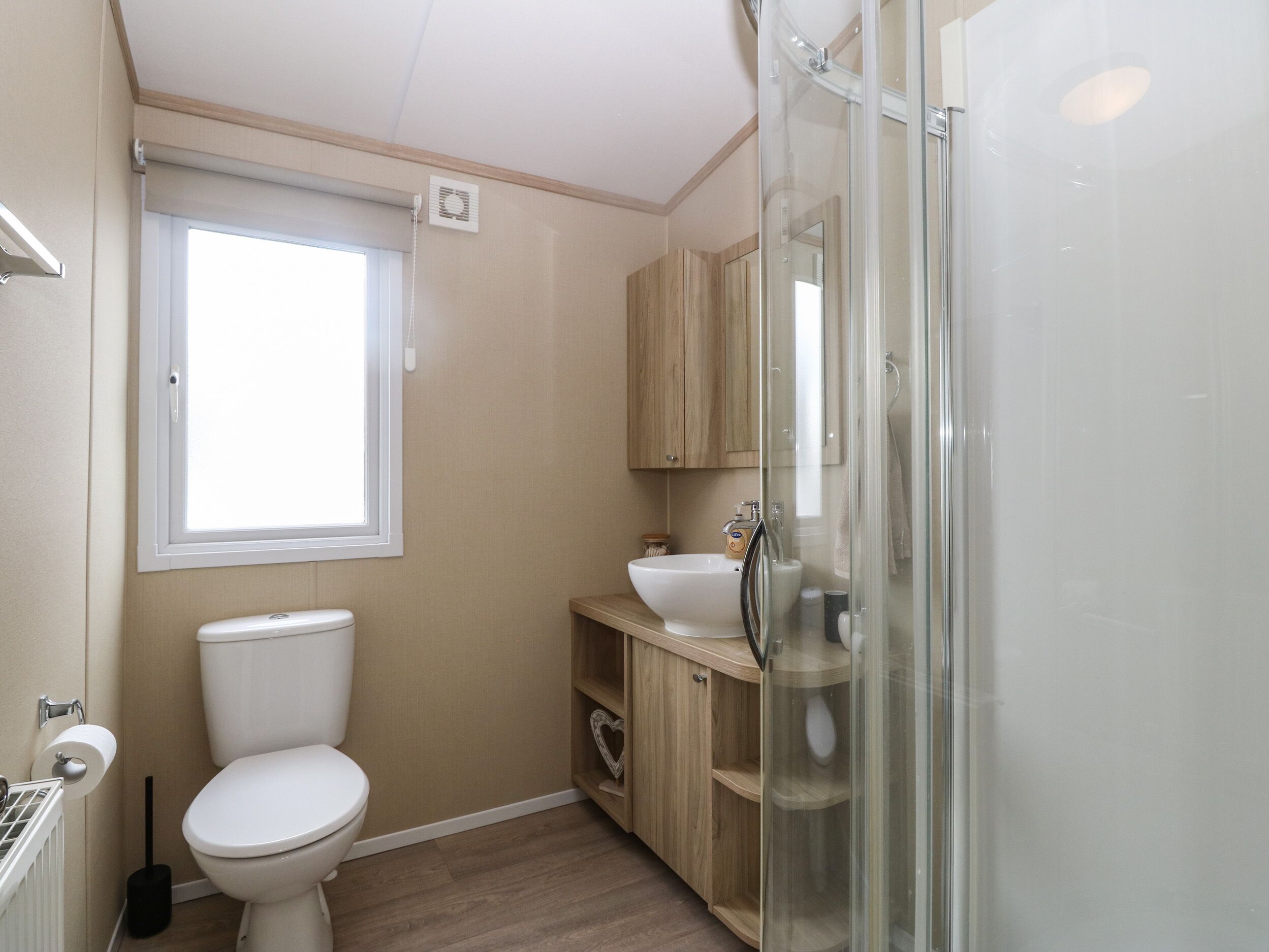 A compact bathroom with a toilet, a sink, and a glass shower enclosure.