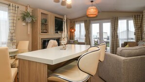 Un salon moderne doté d’une table centrale, d’un coin salon et d’une cheminée.