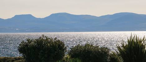 A coastal landscape with a clear view of the sea and distant mountains.