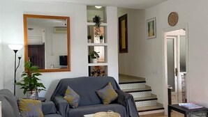 A living room with a grey sofa, a small white table, and a staircase leading to another level.