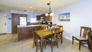 Una cocina con armarios de madera, una isla central y un comedor con mesa y sillas de madera.