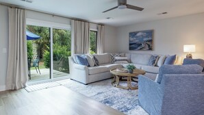 Un salon spacieux, doté d’un grand canapé, d’une table basse et d’un ventilateur de plafond.