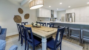 Une cuisine moderne avec des meubles blancs, une table à manger en bois et des chaises bleues.