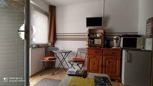 A compact kitchen with a refrigerator, microwave, and a small dining table with chairs. - Tiny Flat Ferienwohnung in Baiersbronn (Baiersbronn)