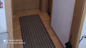 A narrow hallway with a wooden door, a small window, and a mat on the floor. - Tiny Flat Ferienwohnung in Baiersbronn (Baiersbronn)