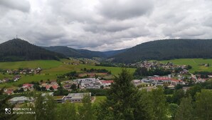 A rural town with houses, a school, and a church surrounded by green hills and a cloudy sky. - Tiny Flat Ferienwohnung in Baiersbronn (Baiersbronn)