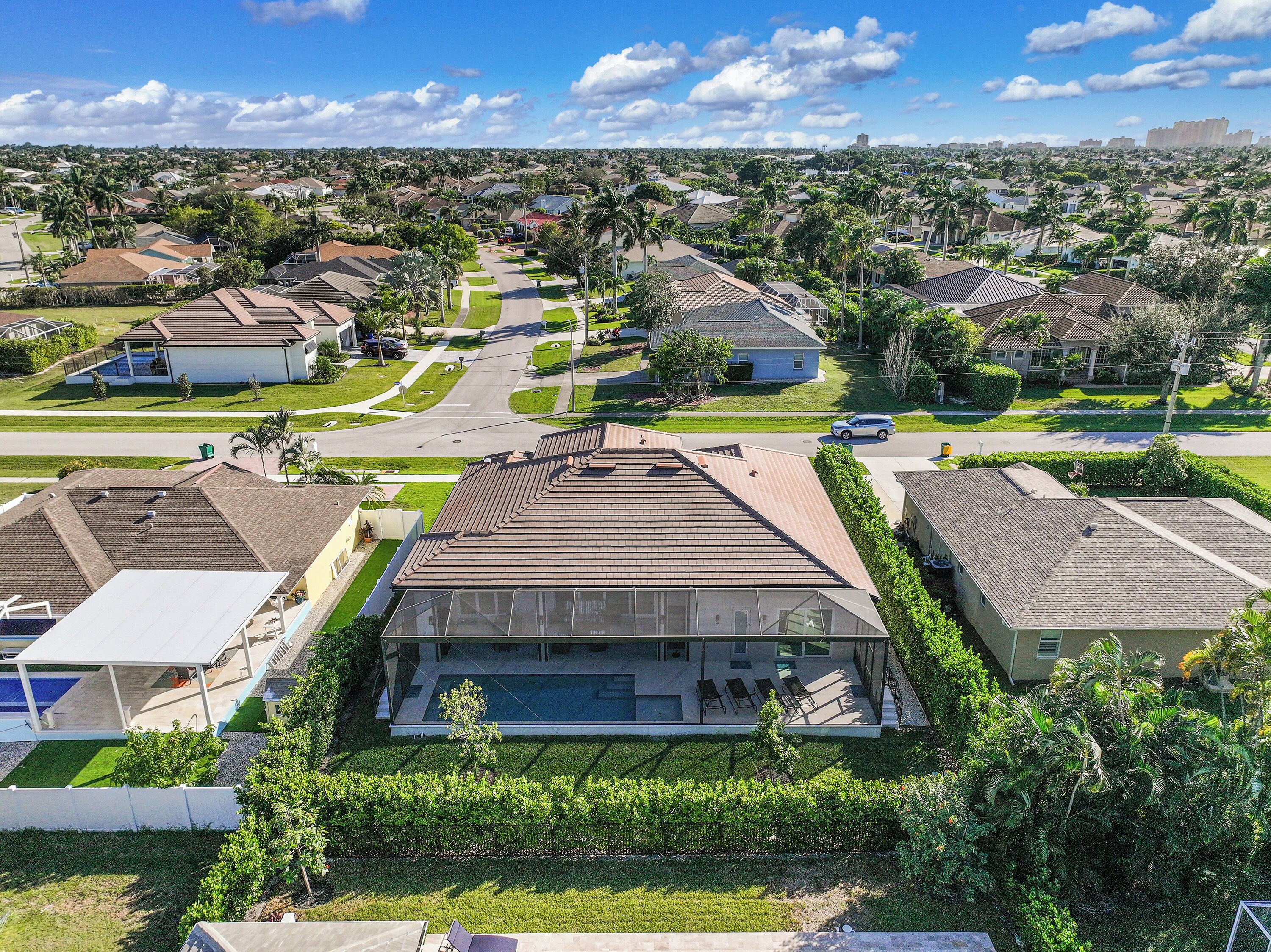 A residential neighborhood with houses, streets, and a large modern building with a swimming pool.