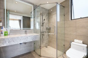 A modern bathroom with a glass-enclosed shower, a sink with a marble countertop, and a toilet.