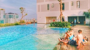 Zona de piscina amb vista a un paisatge urbà, una palmera i un edifici amb nombroses finestres.