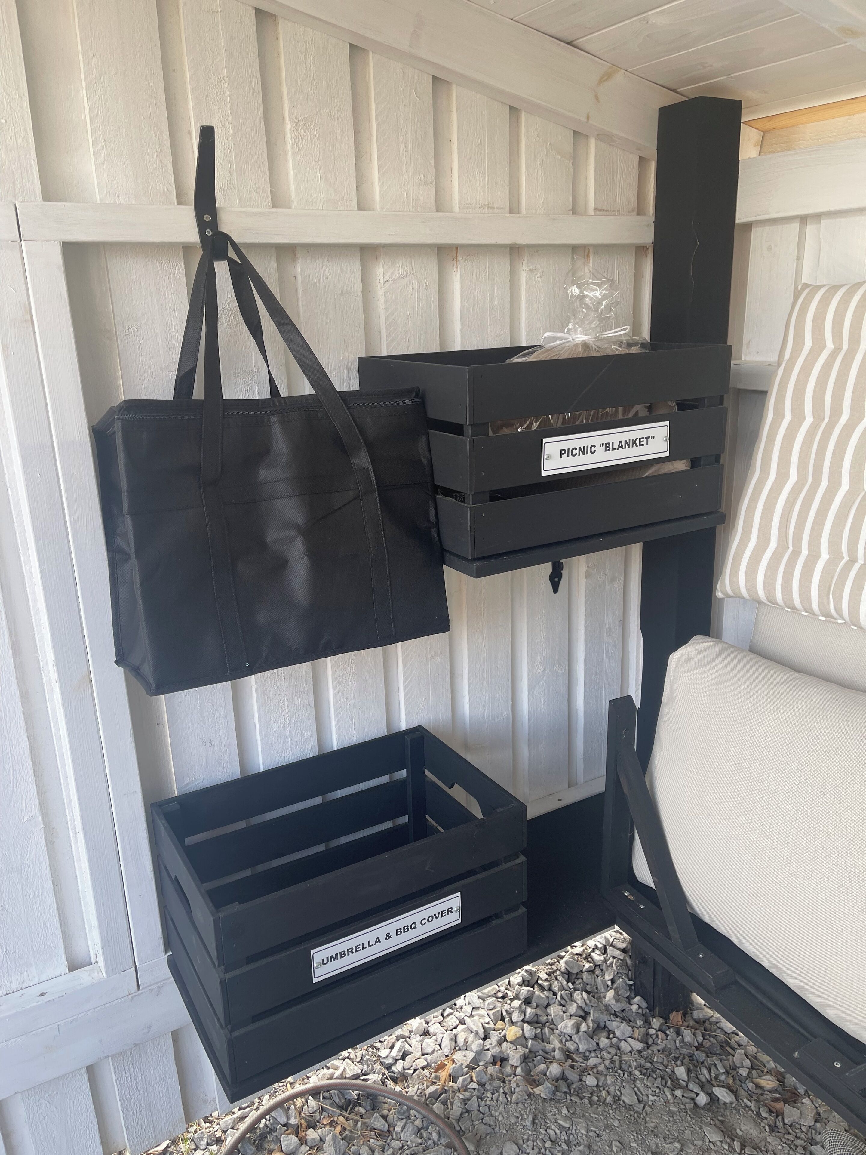 A storage area with labeled bins for picnic blanket and umbrella & BBQ cover.