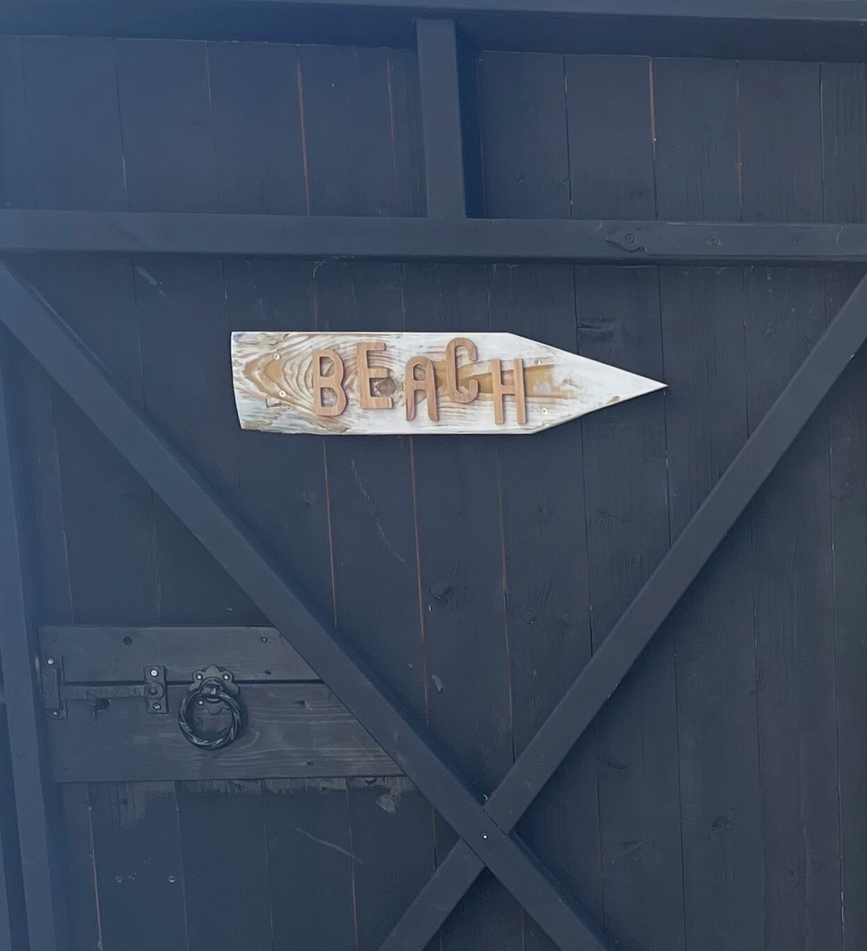 A wooden sign with the word "BEACH" on a dark wooden structure.