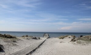 A sandy beach with a wooden pathway leading to the sea.
