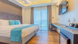 Una habitación de hotel moderna con una cama grande, un escritorio y vistas al exterior.