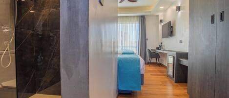 Una camera d'albergo moderna con doccia, letto, scrivania e televisione.