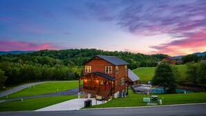 Une cabane en bois à deux étages, dotée d’une véranda et d’une piscine.