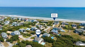 Vue aérienne d’un quartier résidentiel avec des maisons, un accès à la plage et un panneau indiquant les bureaux de Village Realty.