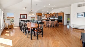 Une cuisine spacieuse avec des meubles en bois, un coin repas doté d’une grande table et de chaises, et une vue sur l’extérieur.