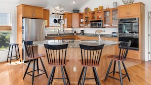 Une cuisine moderne avec des meubles en bois, des appareils en acier inoxydable et un îlot central doté de tabourets de bar.