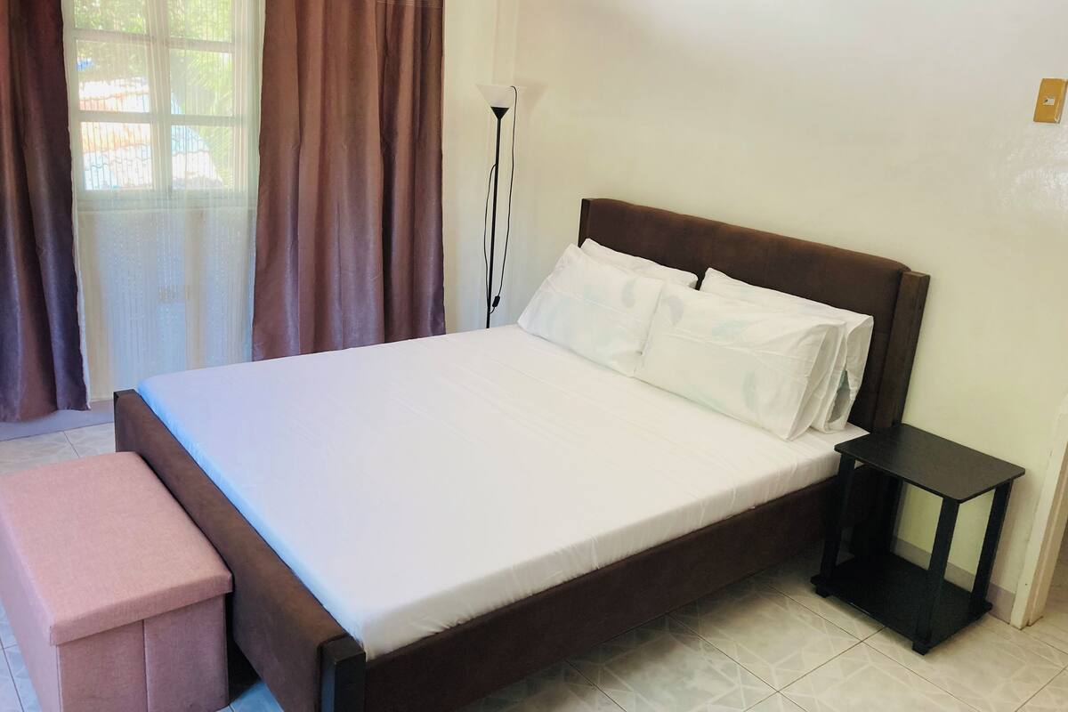 A neatly made bed with white linens, a wooden headboard, and a small bedside table.