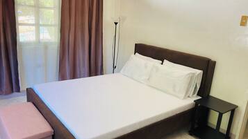 A neatly made bed with white linens, a wooden headboard, and a small bedside table.