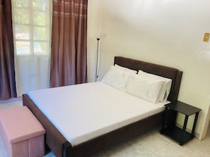 A neatly made bed with white linens, a wooden headboard, and a small bedside table.