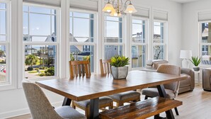 A spacious dining area with a wooden table, multiple chairs, and a potted plant. - Across the Pond | Private Pool + Near Beach (Surf City)