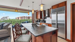 A modern kitchen with a large island, stainless steel appliances, and a view of a cityscape.