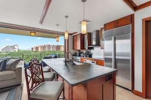 A modern kitchen with a large island, stainless steel appliances, and a view of a cityscape.