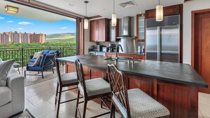 A modern kitchen with a large island, stainless steel appliances, and a view of a residential area.