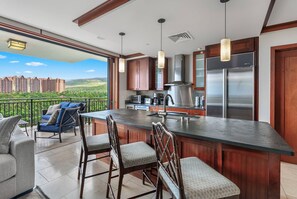 A modern kitchen with a large island, stainless steel appliances, and a view of a residential area.